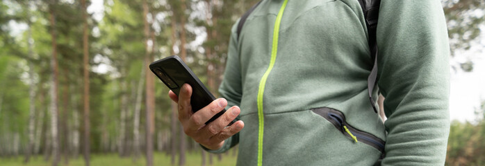 Person using mobile phone in forest 