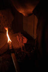 A man holds a torch and checks the spices stored in a warehouse