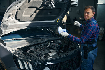 Man checking oil level in vehicle engine