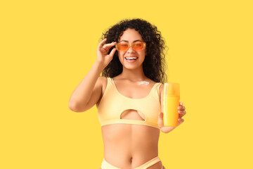 Naklejka premium Young African-American woman with sunscreen cream on yellow background