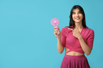 Young woman with mini fan on blue background
