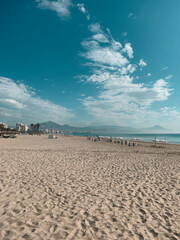 landscape of a yellow beach with mountains and blue sea and palm trees