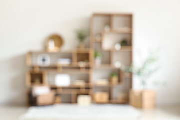 Fototapeta premium Blurred view of wooden bookshelf with artificial plants in light room