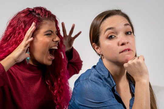 Mujer molesta y furiosa gritandole a su amiga mientras ella tiene cara de fastido