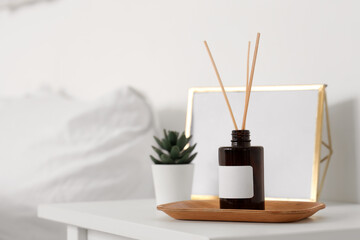 Reed diffuser, houseplant and photo frame on bedside table at home
