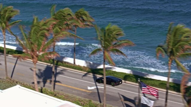 Establishing aerial rolling shot of supercar driving in Miami West Palm Beach on a sunny day. Epic drone footage of supercar driving on Miami Sunny Streets