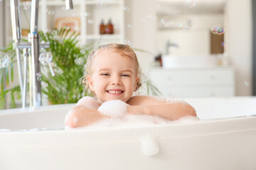 Cute little girl taking bath with foam and soap bubbles taking bath in bathroom
