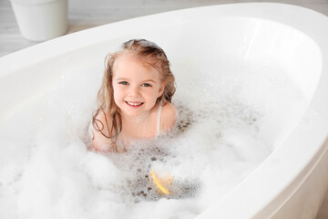 Cute little girl with foam taking bath in bathroom