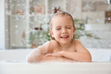 Cute little girl with soap bubbles taking bath in bathroom