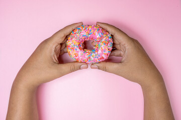 Human hand holding a delicious donut with a colorful sprinkle decoration