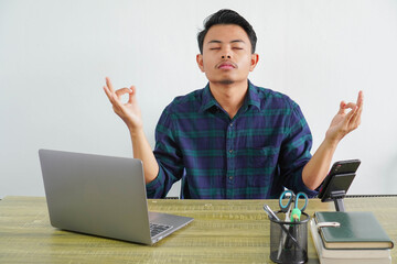 relaxed young asian man in blue shirt sit work at wooden desk with pc laptop. Achievement business...