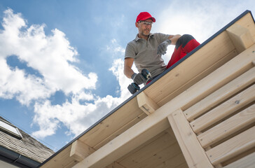 Construction Worker on Roof Using Drill