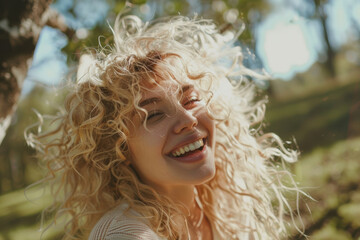 Fototapeta premium Sunlight illuminates a joyful woman's curly hair, capturing her infectious laughter.