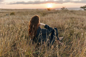 Serene woman watching sunset in peaceful field, contemplating the beauty of nature