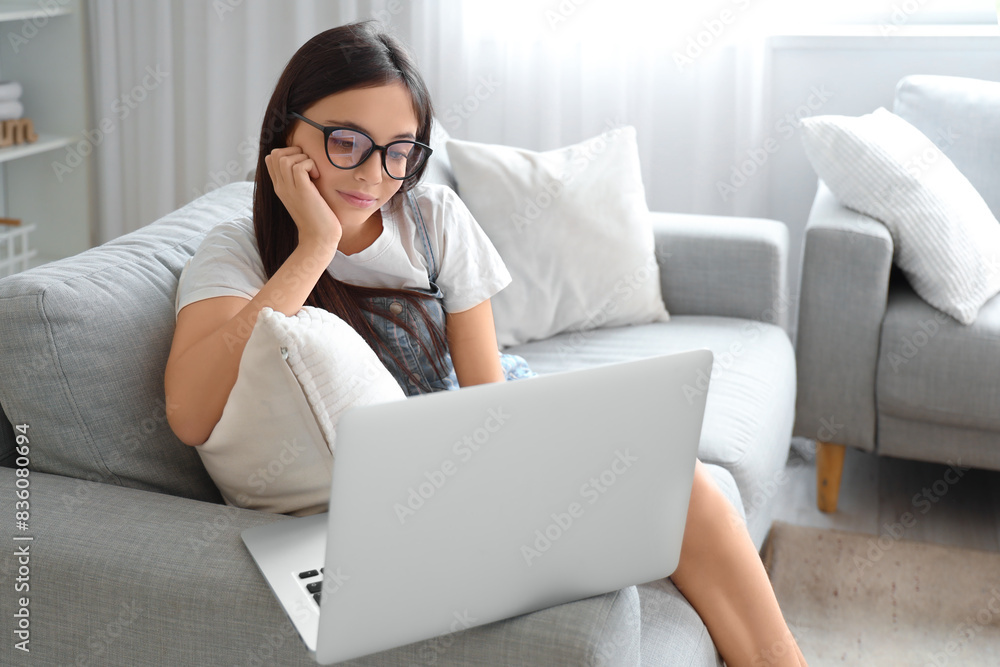 Poster Little schoolgirl using sofa on sofa at home