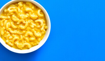 Mac and cheese in bowl over blue background