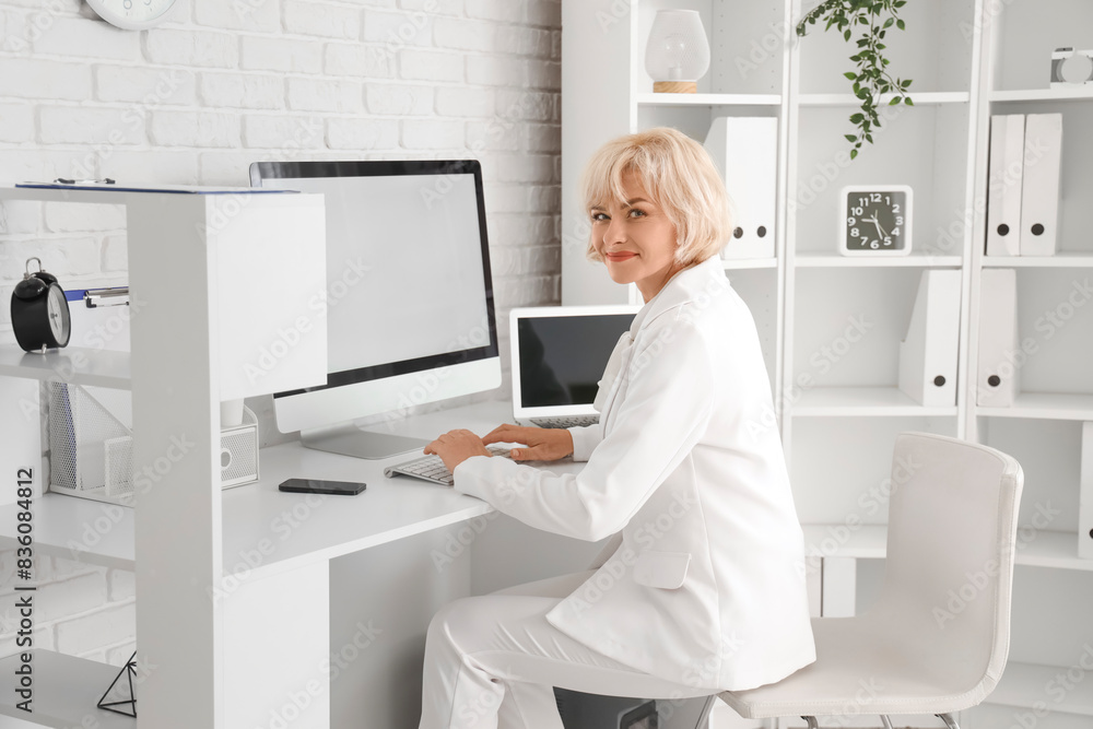 Poster Mature businesswoman working with computer at table in office