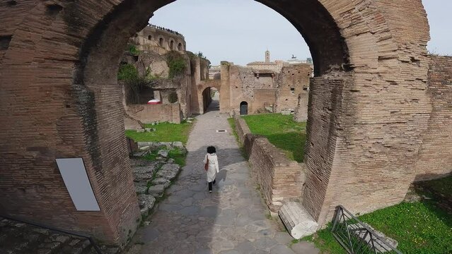 Fashion stylish female model walk visiting ancient Roman Forum in Rome, Italy, aerial drone view