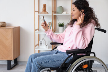 Young African-American woman in wheelchair with mobile phone video chatting at home