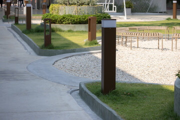 light bollard on a walkway with a gravel path and a row of benches.