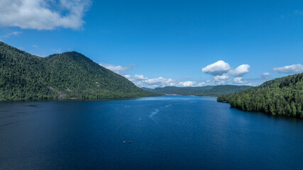 beautiful landscape with mountains and Lake Teletskoye against a background of blue sky from a drone in May
