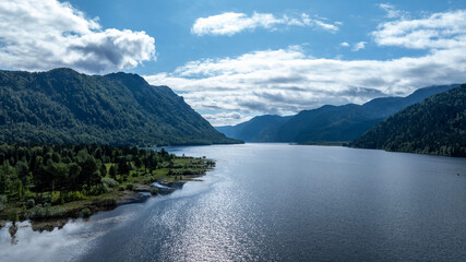 beautiful landscape with mountains and Lake Teletskoye against a background of blue sky from a drone in May