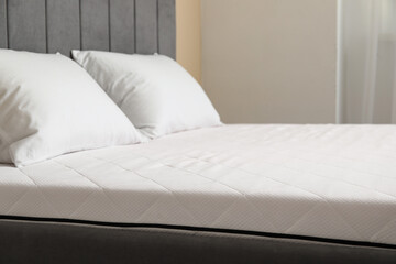 New orthopedic mattress with pillows on stylish bed in room, closeup