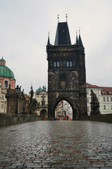 Naklejka premium Charles Bridge with wet paving stones and historical buildings in rainy weather