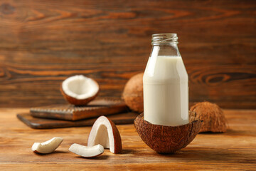 Bottle of natural coconut milk on brown wooden background