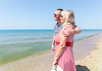 An elderly man and woman hugging on the seashore on a sunny day. Love and tenderness. A happy...