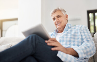 Smile, tablet and mature man on sofa for communication, networking or reading news article in...