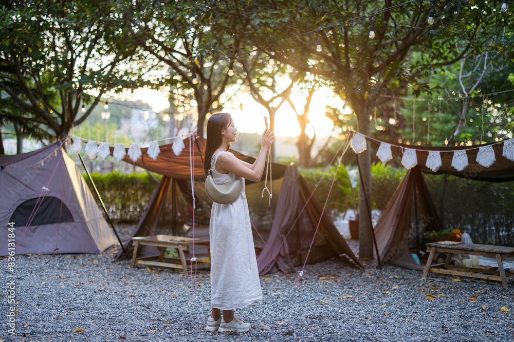 Wall mural Woman use mobile phone to take phone under sunset