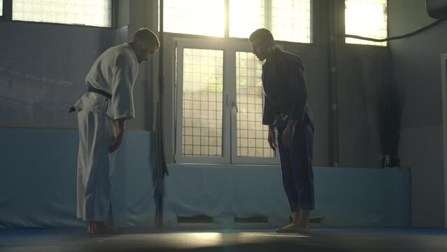 Two men showing respect to each other while training their aikido skills. Parries the hit and throwing the opponent on the floor in slow-motion