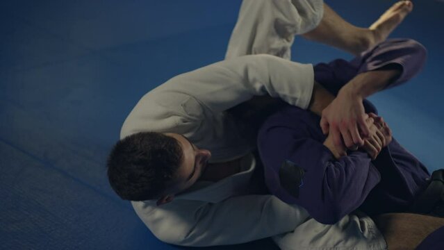 Fighter training combat sparing on the ground in slow-motion. Kimura submission control arm lock from guard detail