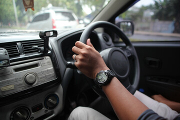 close up of a husband's hand holding the steering wheel of a car while driving, right steering wheel