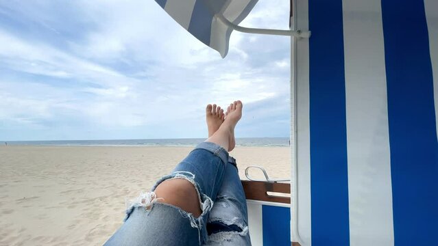 barefoot in a deckchair on the beach