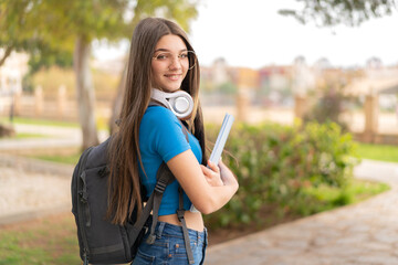 Teenager girl at outdoors holding a notebook