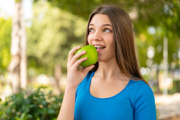 Teenager girl at outdoors holding an apple