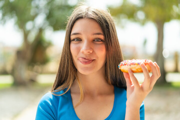 Teenager girl at outdoors holding a donut
