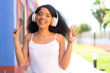 Young African American woman with headphones at outdoors showing victory sign with both hands