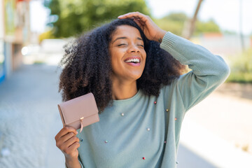 Young African American woman holding a wallet at outdoors has realized something and intending the...