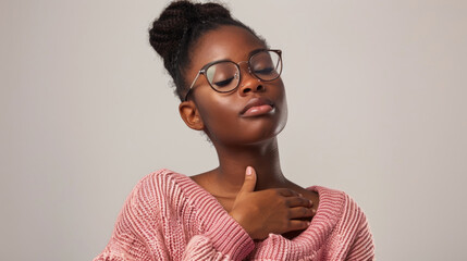 Obraz premium A young woman wearing glasses and a pink sweater closes her eyes and takes a deep breath, enjoying a moment of peace and tranquility.