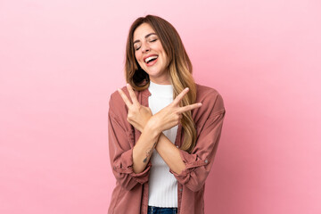Caucasian woman isolated on pink background smiling and showing victory sign