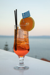 A glass of Aperol spritz cocktail on the background of the sea and sky in the evening.