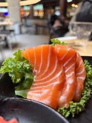 Salmon sashimi on black plate, japanese food in restaurant.