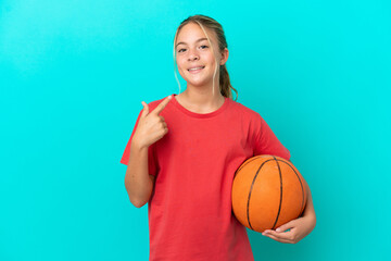 Little caucasian girl playing basketball isolated on blue background giving a thumbs up gesture