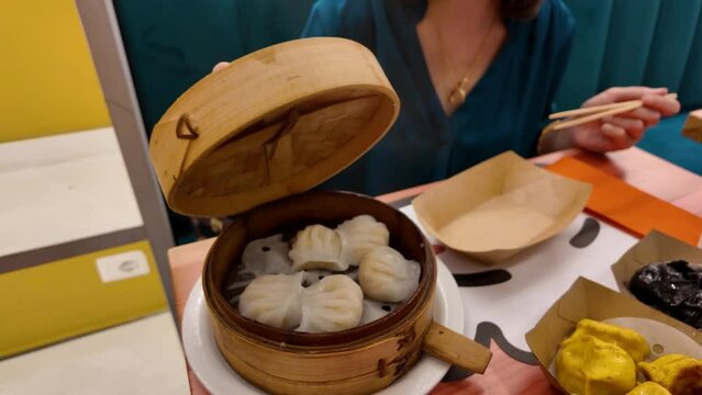 Woman's hands lift the lid of traditional Chinese dumplings. Shumai is a type of traditional Chinese dumpling. Cantonese cuisine food is usually served with dim sum. Stuffed with meat or fish veget