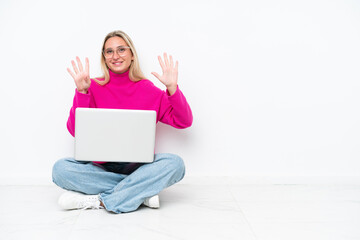 Young caucasian woman with laptop sitting on the floor counting nine with fingers