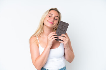 Young caucasian woman isolated on white background taking a chocolate tablet and happy