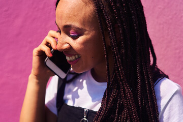 Happy, woman and phone call at wall for conversation, joke and comedy with closeup on pink...